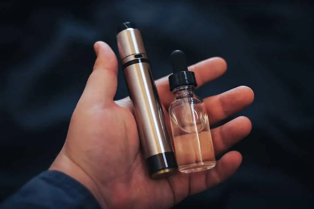 A person holding a small bottle of vape juice