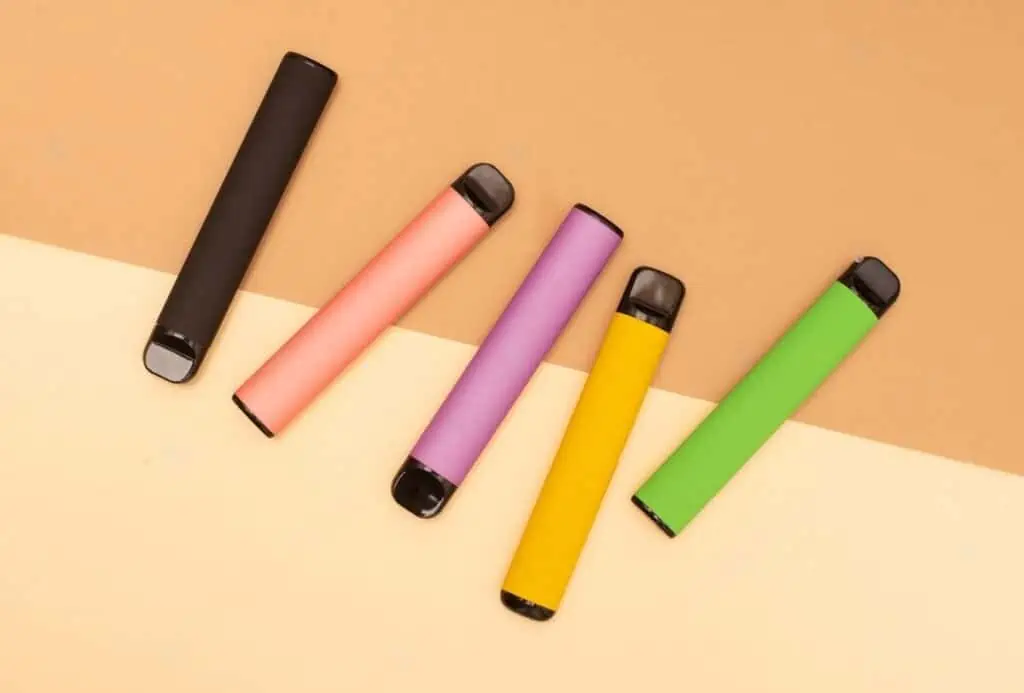 colorful disposable electronic cigarettes on a beige background