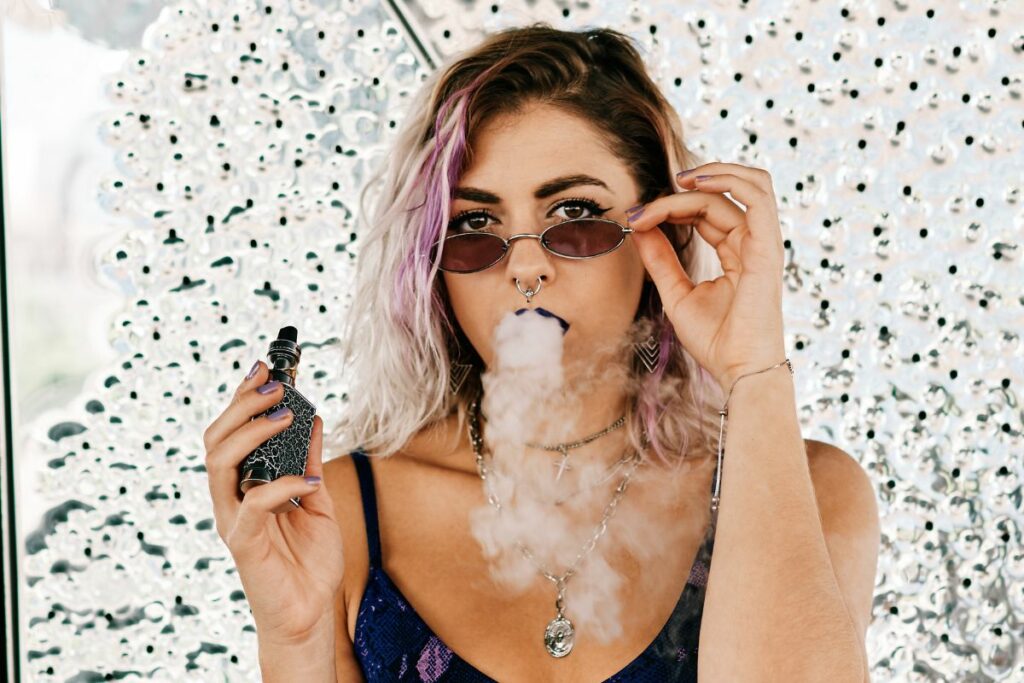A woman vaping for the first time with smoke coming out of her mouth.