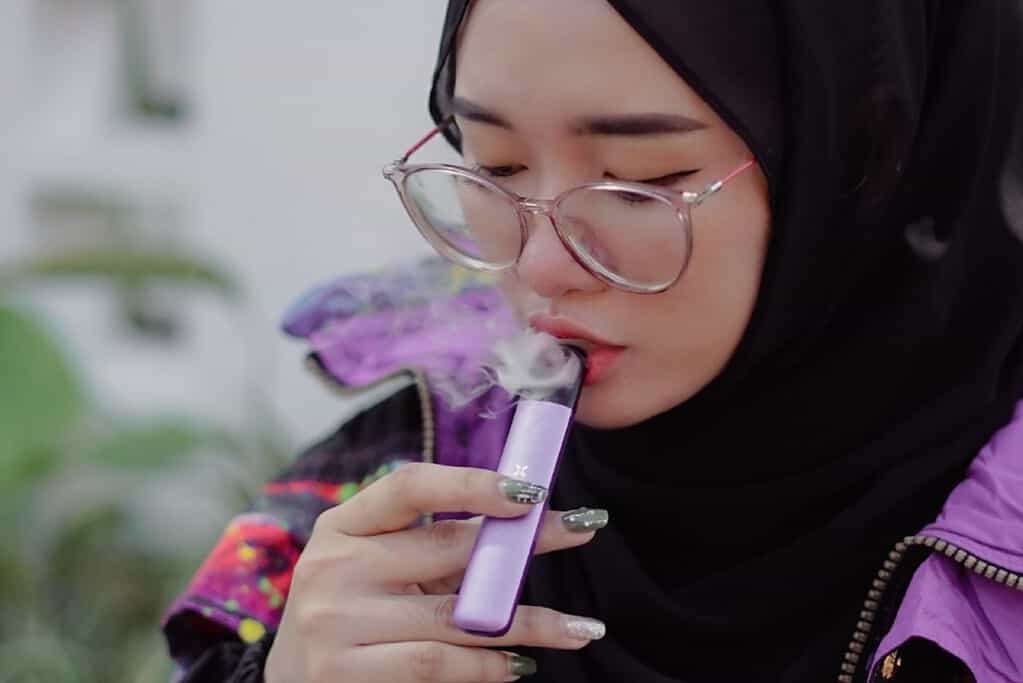 A woman in a hijab vaping outdoor
