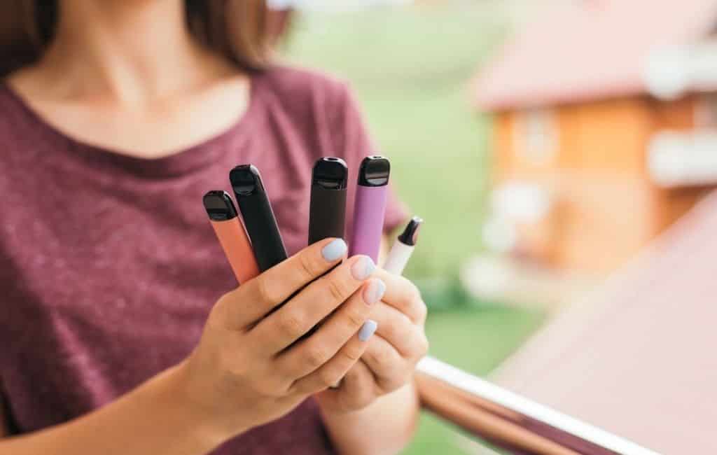 Many different disposable e-cigarettes in hand