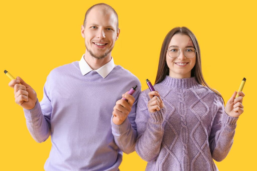 A guy and a girl holding disposable vapes
