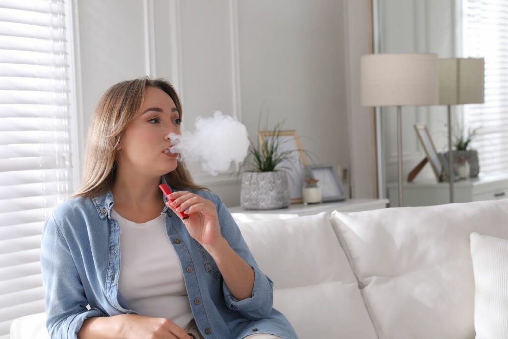 A woman sitting on a sofa and vaping
