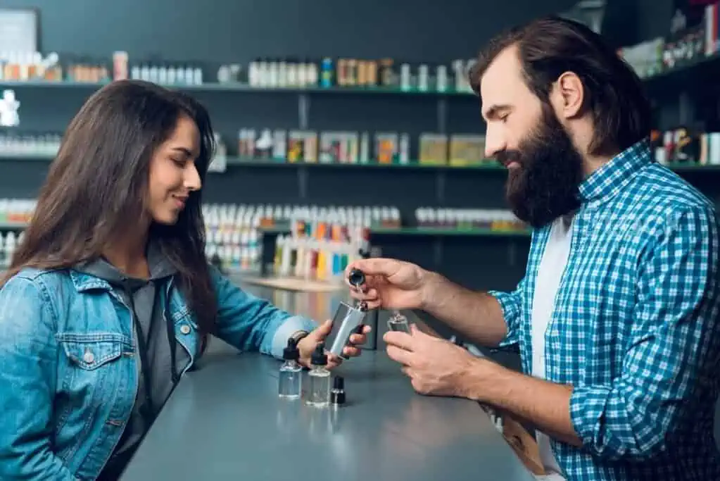 A man and woman inquire about ID requirements for purchasing a vape at the shop's counter.