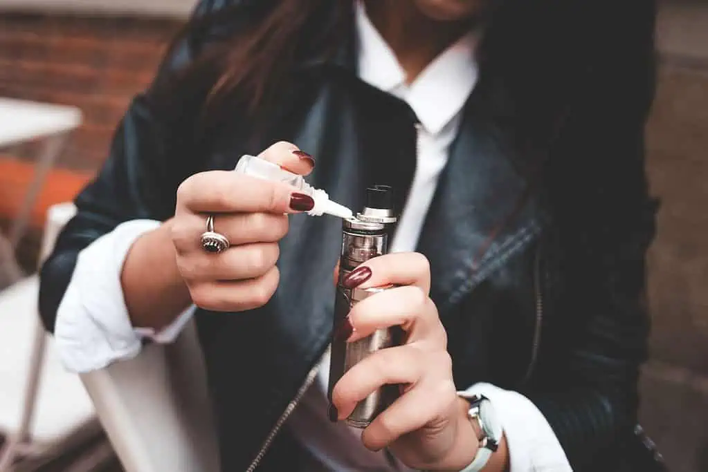 A woman in a leather jacket is holding the best discreet vape.