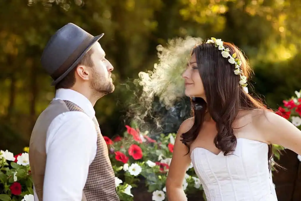 A bride and groom vaping in a park for their wedding photos.