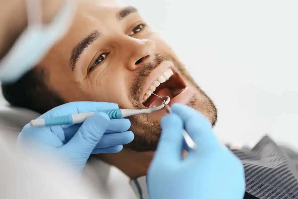 A dentist checks if a man vapes during his teeth examination.