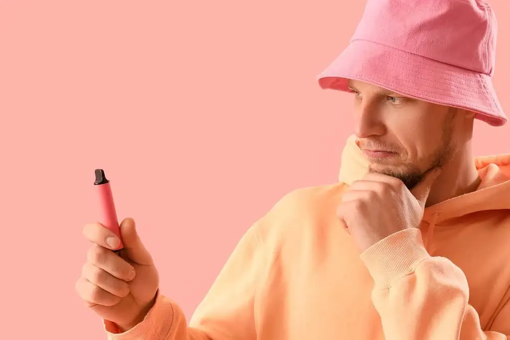 A guy holding a disposable vape and thinking how long will it last