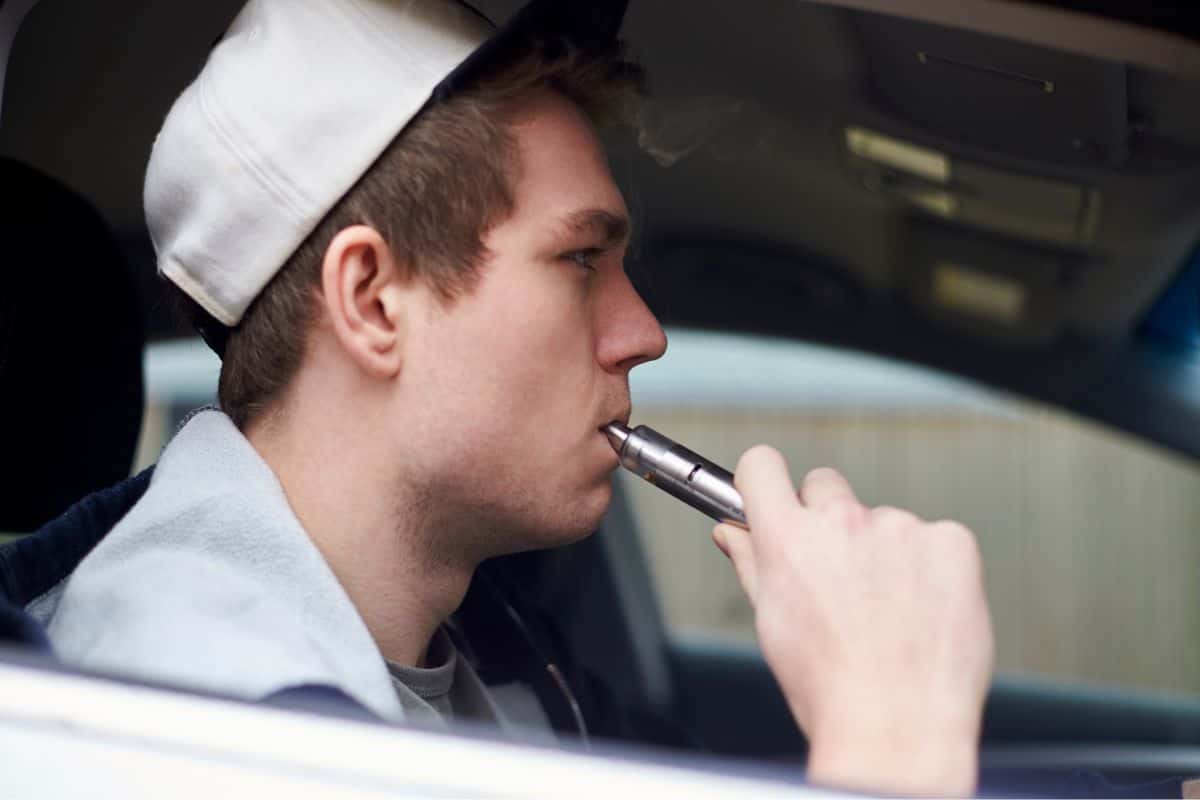 A young man leaving a vape in a hot car.