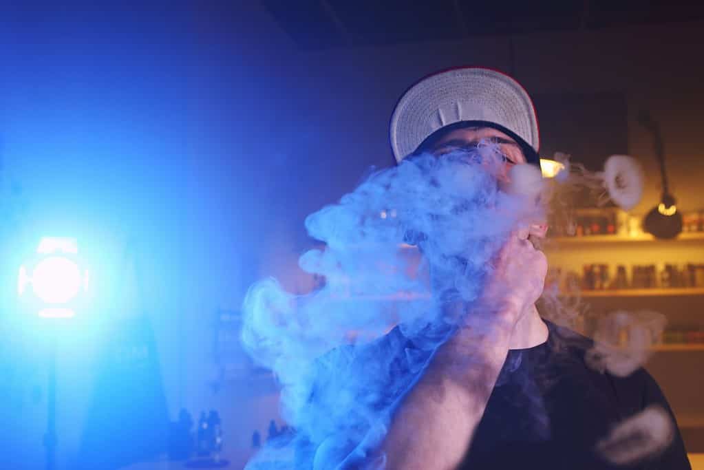 A man smoking a vaporizer in a dark room.