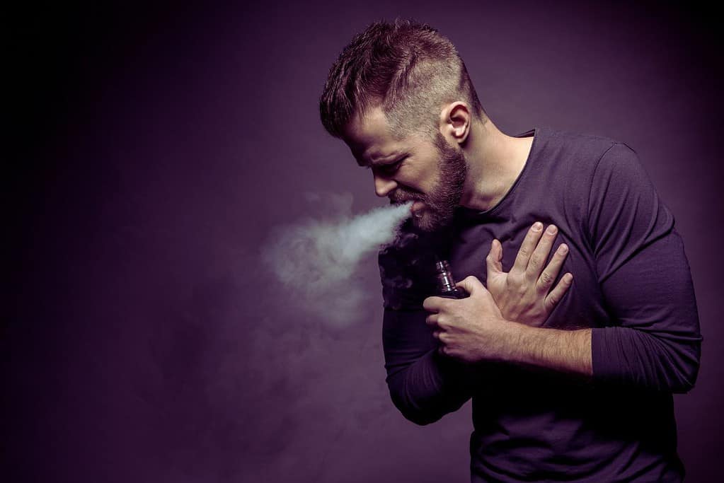 A guy vaping and feeling its side effects