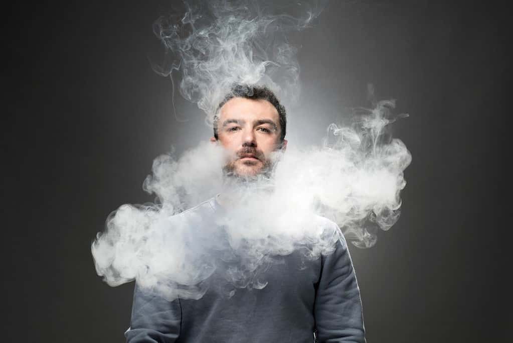 A guy vaping and inhaling vapors
