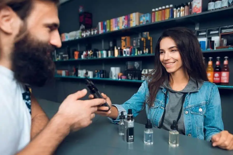 A man and woman discussing whether an ID is required to purchase a vape in store.