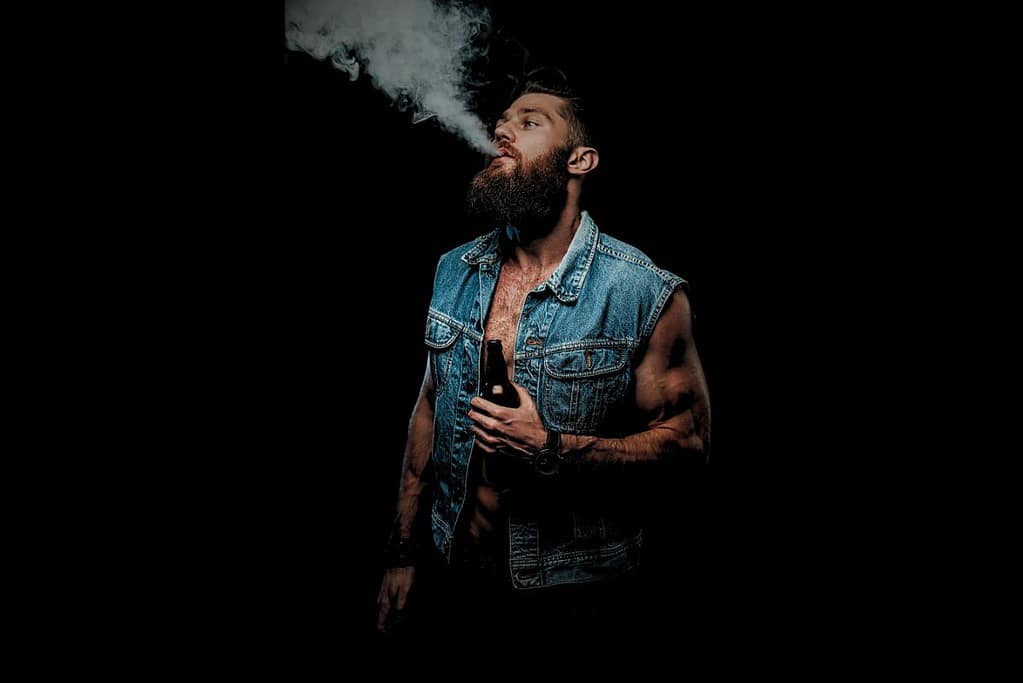 A man vaping on a black background.