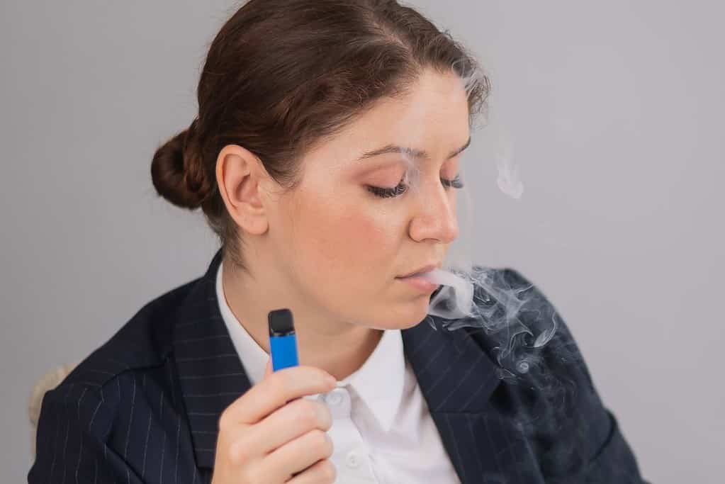 A woman vaping while working on her laptop