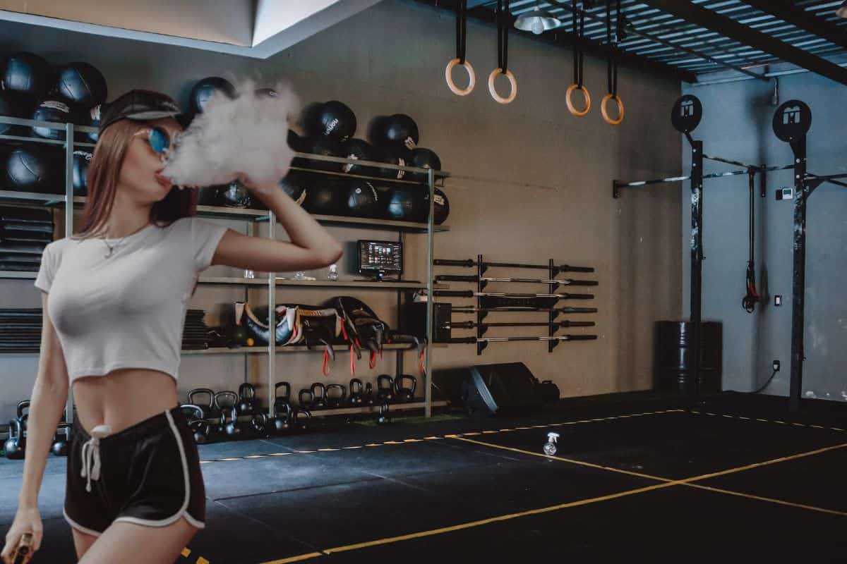 A young woman vaping in the gym and having a good time