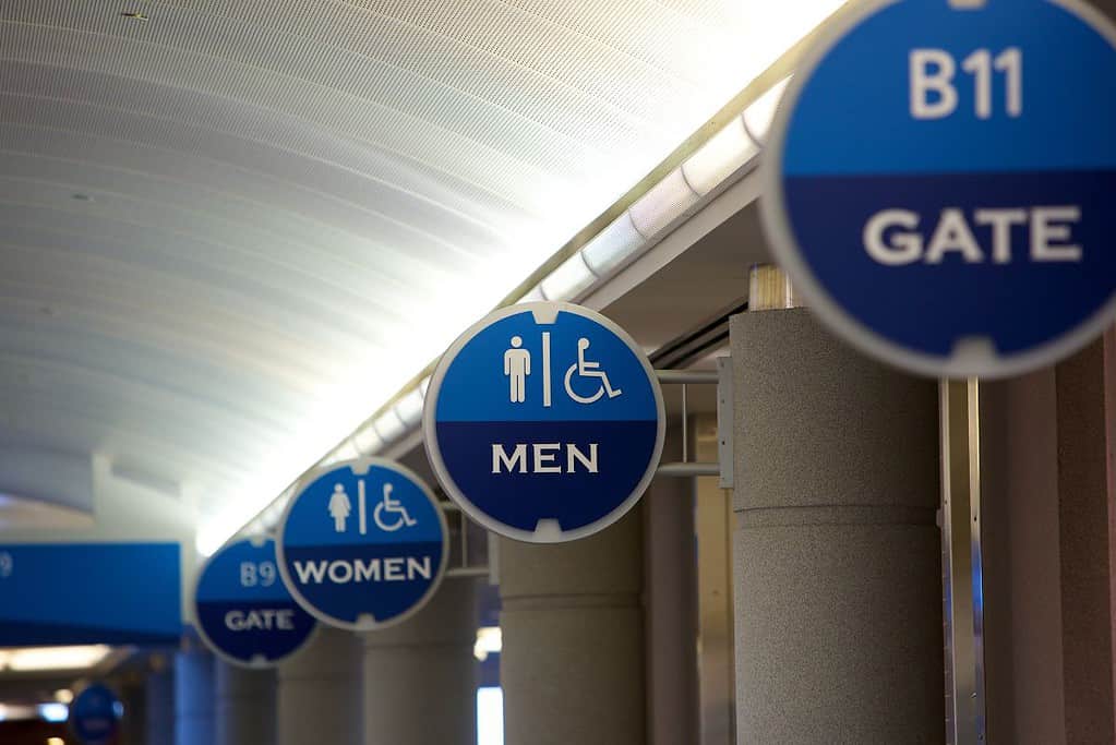 A group of signs hanging from a ceiling in an airport.