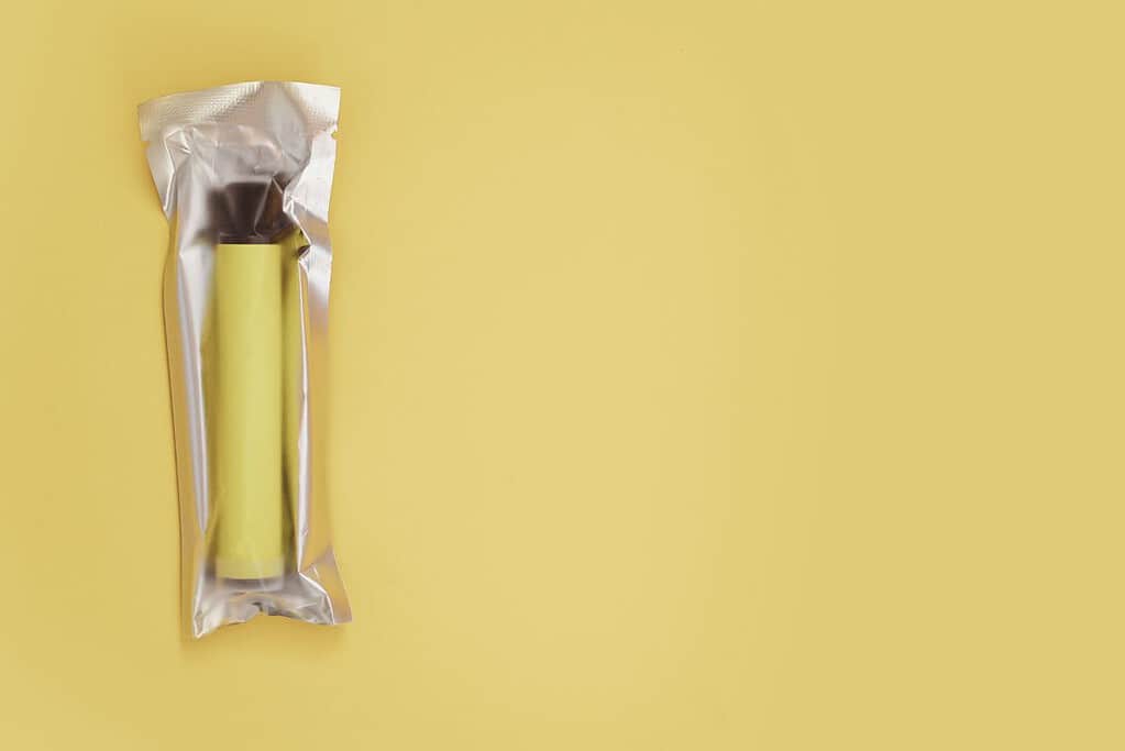 A foil wrapped banana on a yellow background.