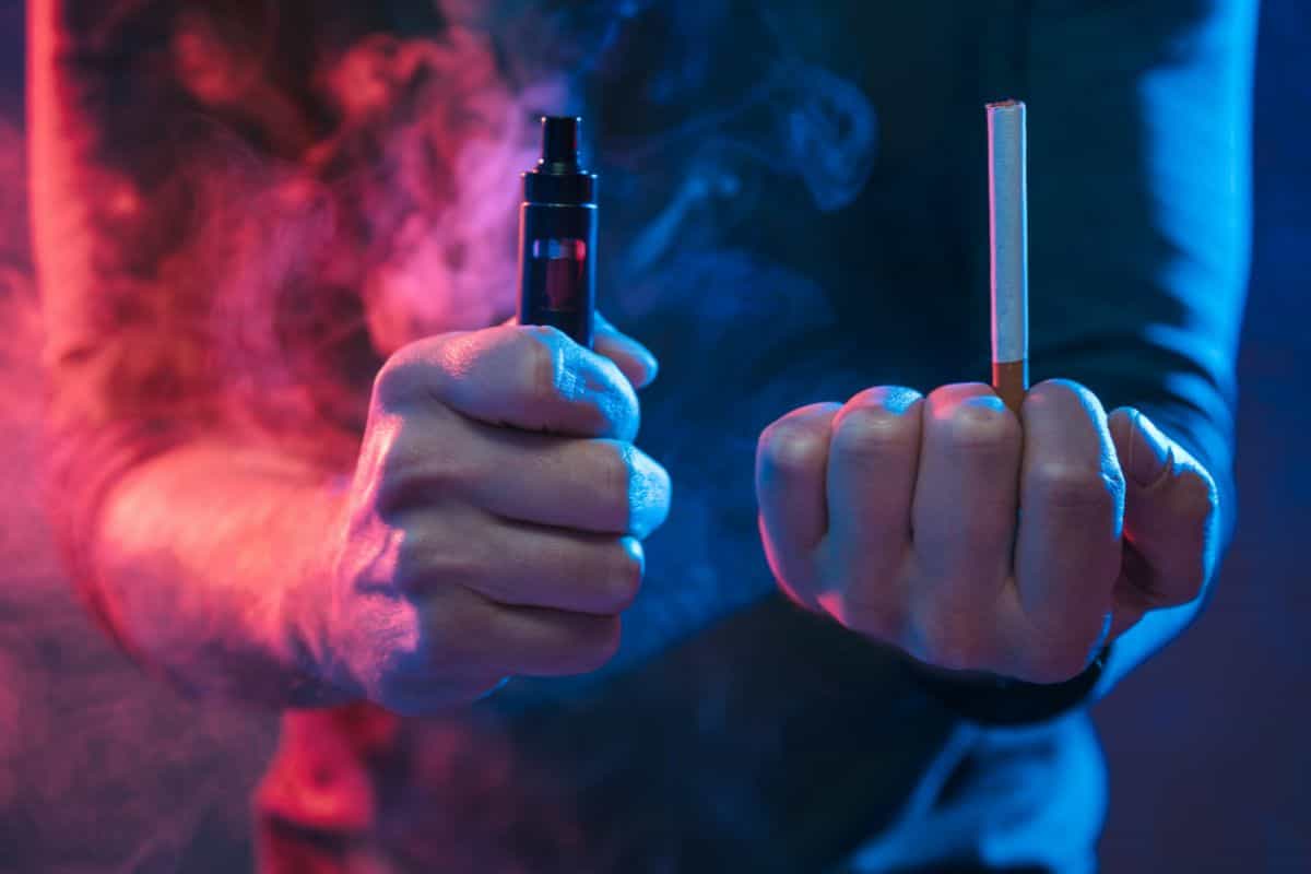 A man holding both vape and cigarette to know vape to cigarette puff conversion