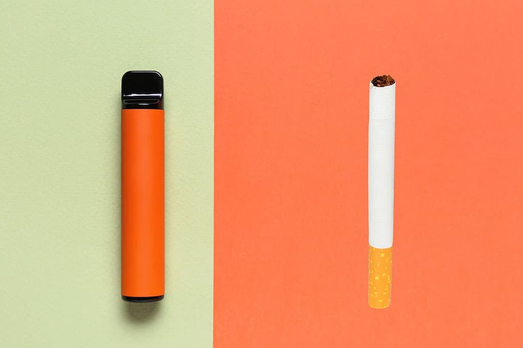 A cigarette and an electronic cigarette on a colorful background