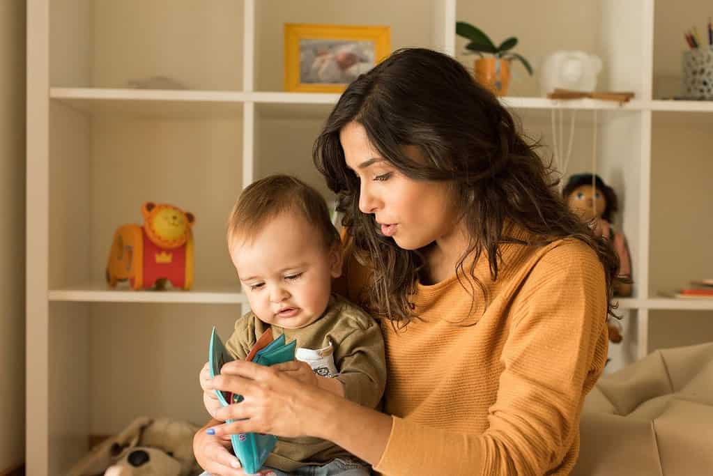 A woman is holding a baby and playing with a toy