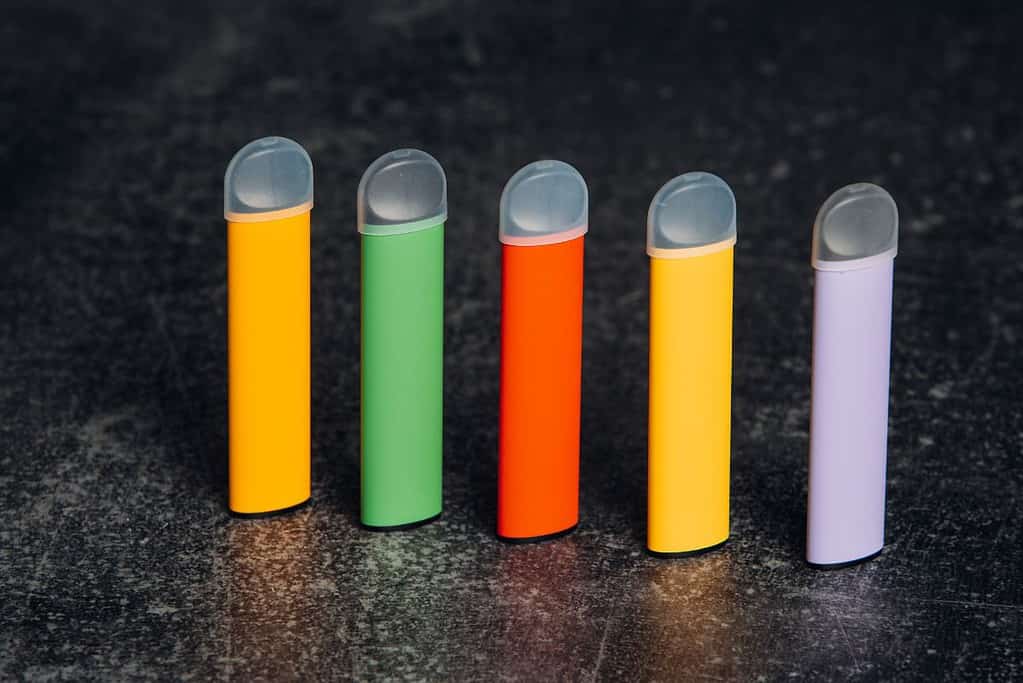A group of colorful e cigarettes on a black surface